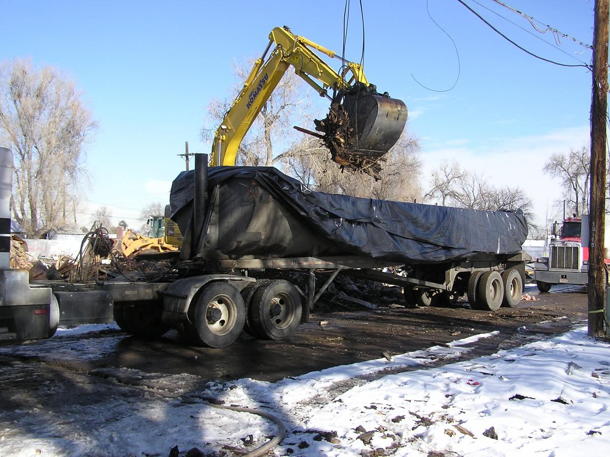 Loading a poly-lined, tarped haul trailer with impacted material