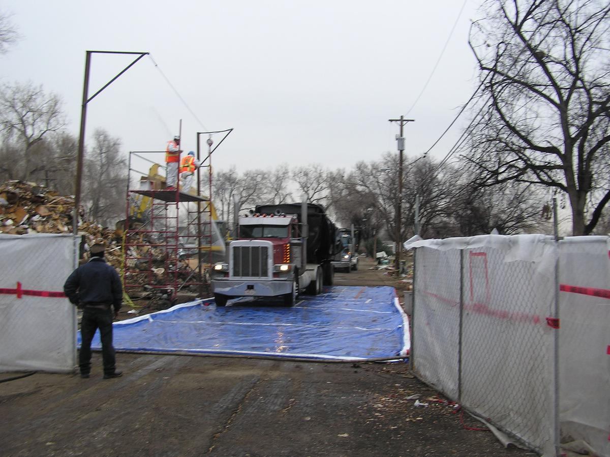 Truck exiting over a lined decontamination pad through containment fencing
