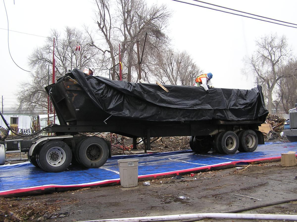 Crew covering a loaded trailer with poly sheeting