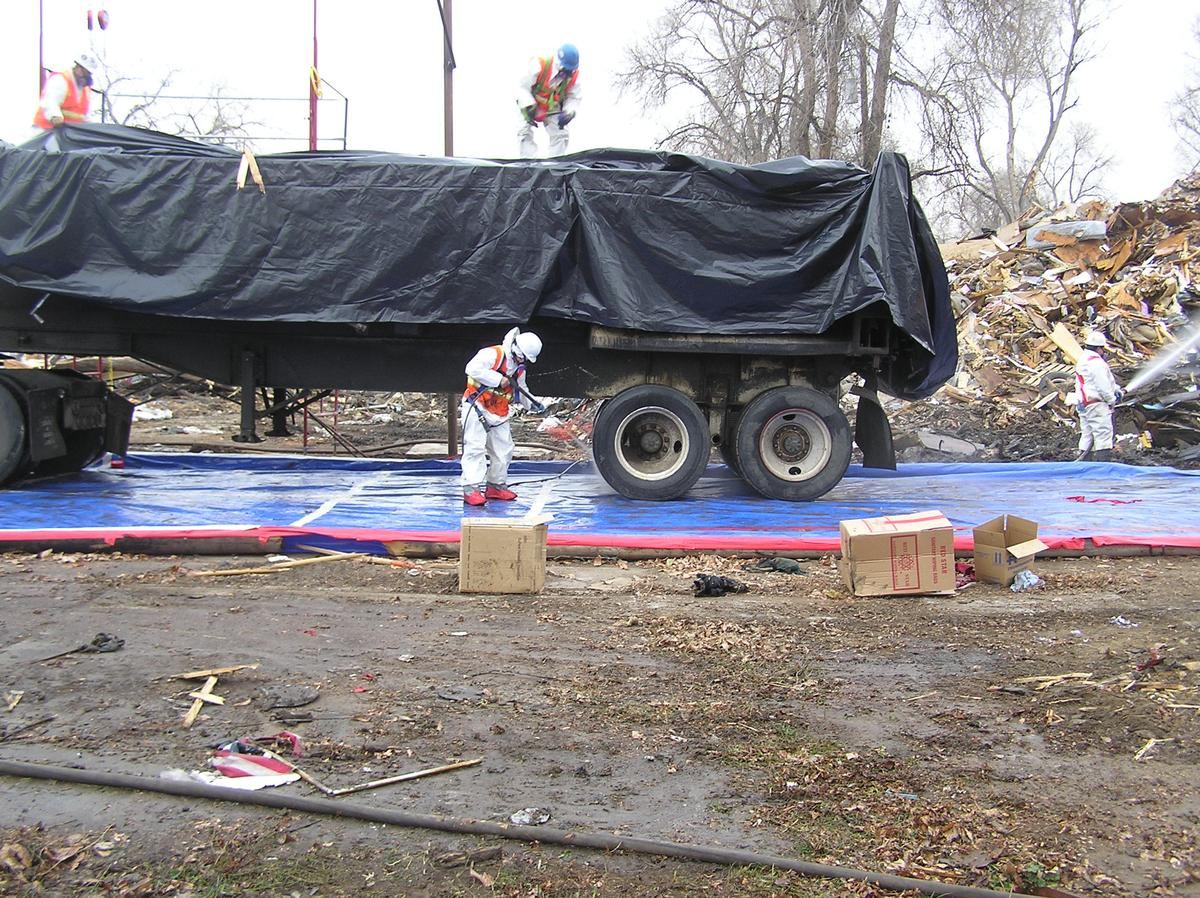 Tyvek-suited worker decontaminating a trailer on a lined pad
