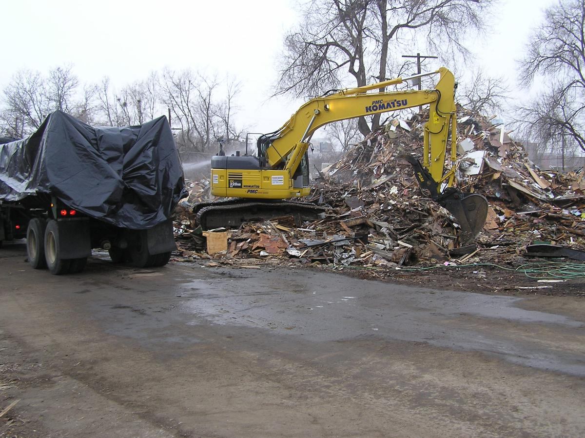 Excavator wetting a debris pile for dust control