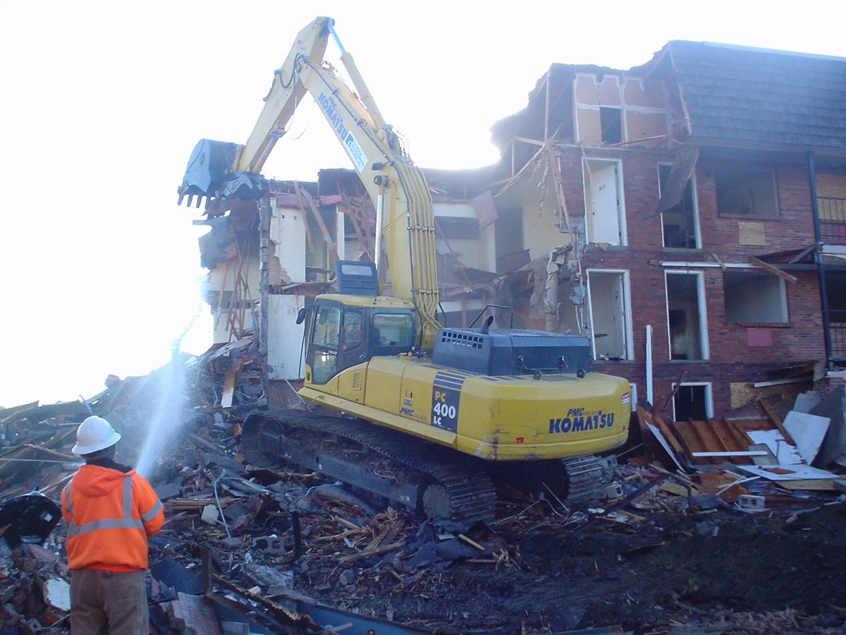 High-reach excavator demolishing a brick apartment building