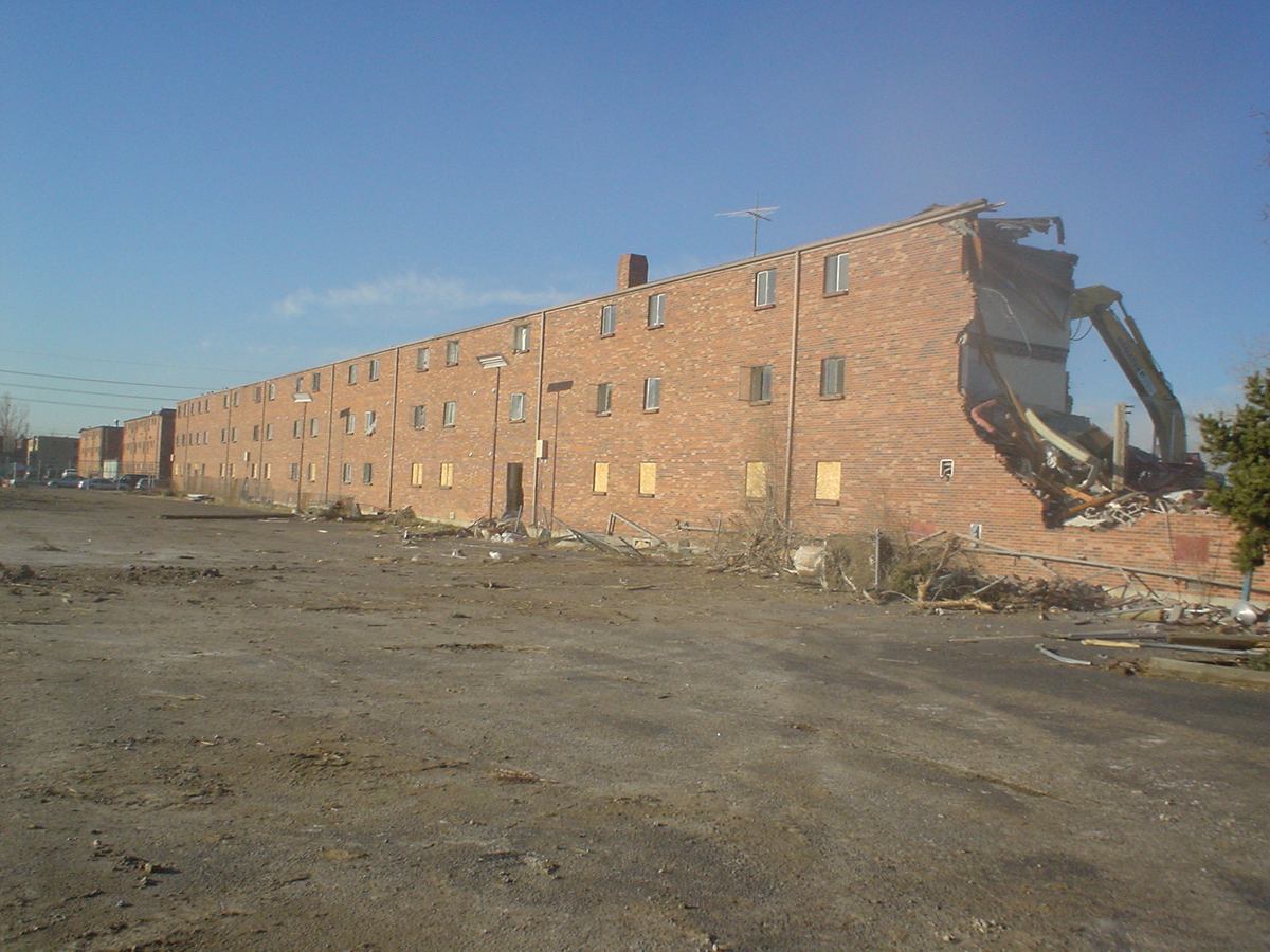 Large multi-story brick apartment complex being demolished