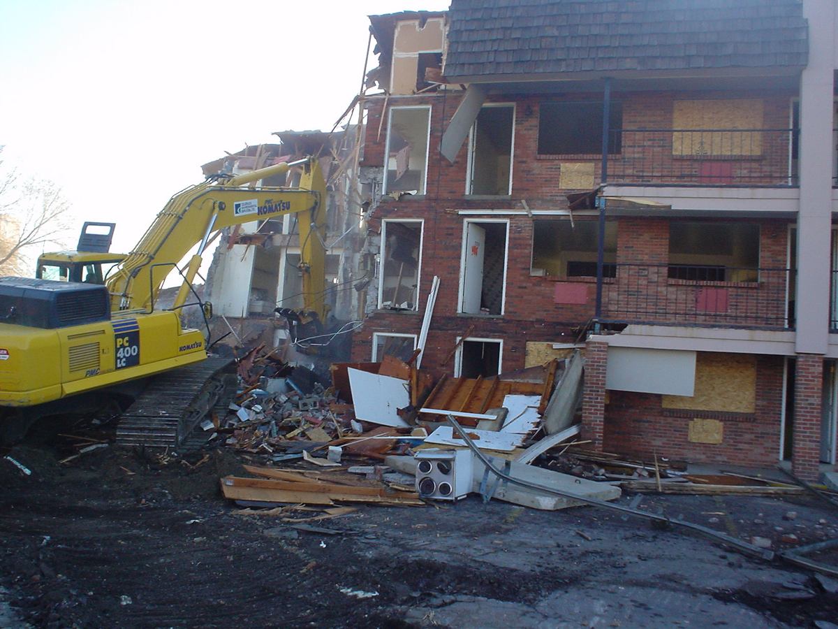 Excavator tearing down a brick-and-timber apartment structure