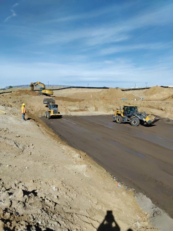 Excavator, loader and laborer working a mass excavation