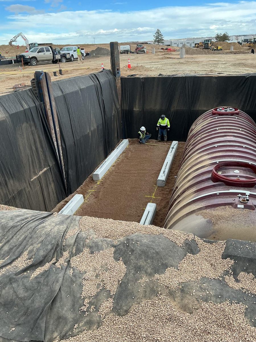 Shored fuel tank excavation with bedding and concrete hold-down anchors
