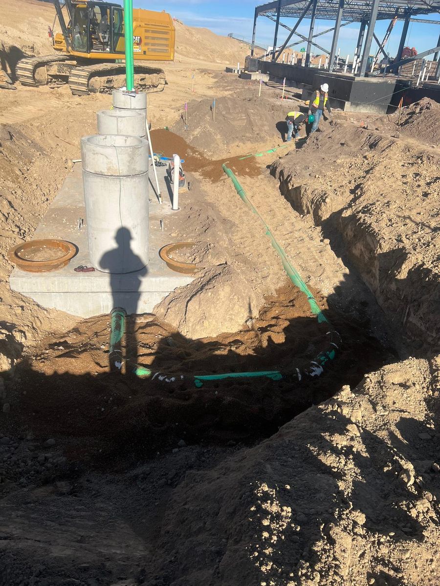 Grease interceptor set with access risers and sewer pipe routed around it
