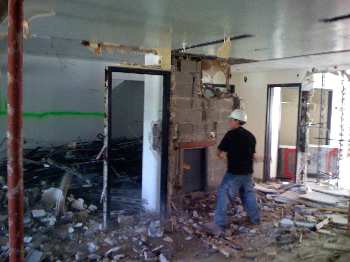 Worker removing a CMU partition wall during interior demolition