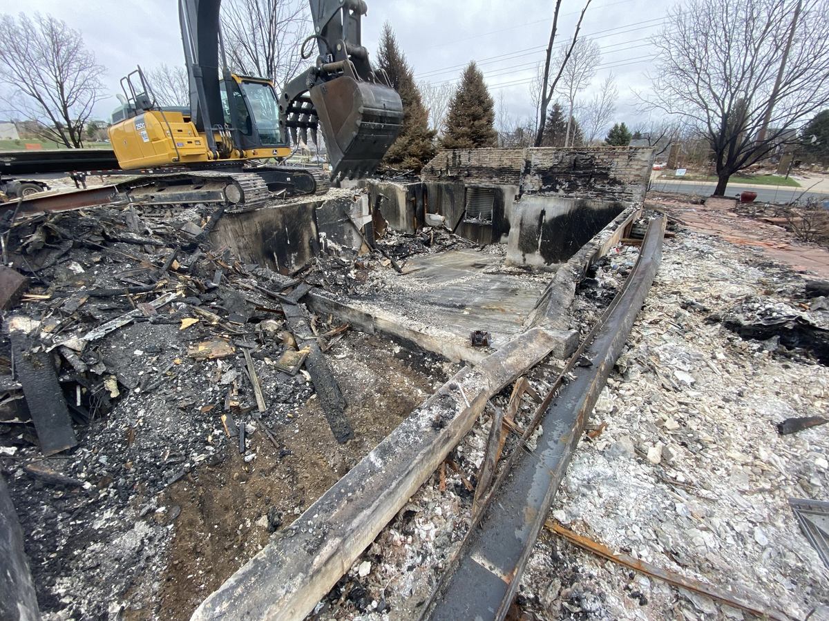 Debris removal in progress on a fire-damaged lot