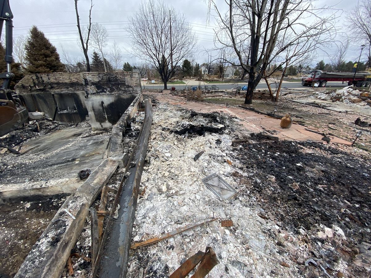 Skid steer clearing a burned residential site