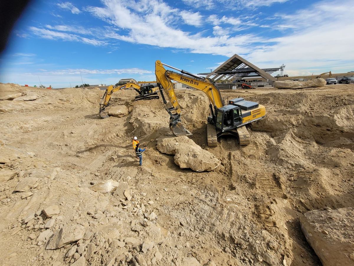 Excavators removing oversized boulders from a deep cut