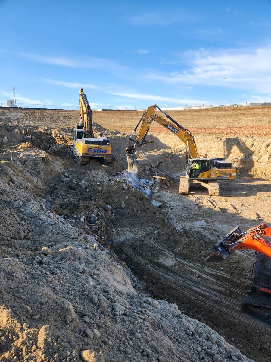 Excavators breaking and removing rock in a deep pit