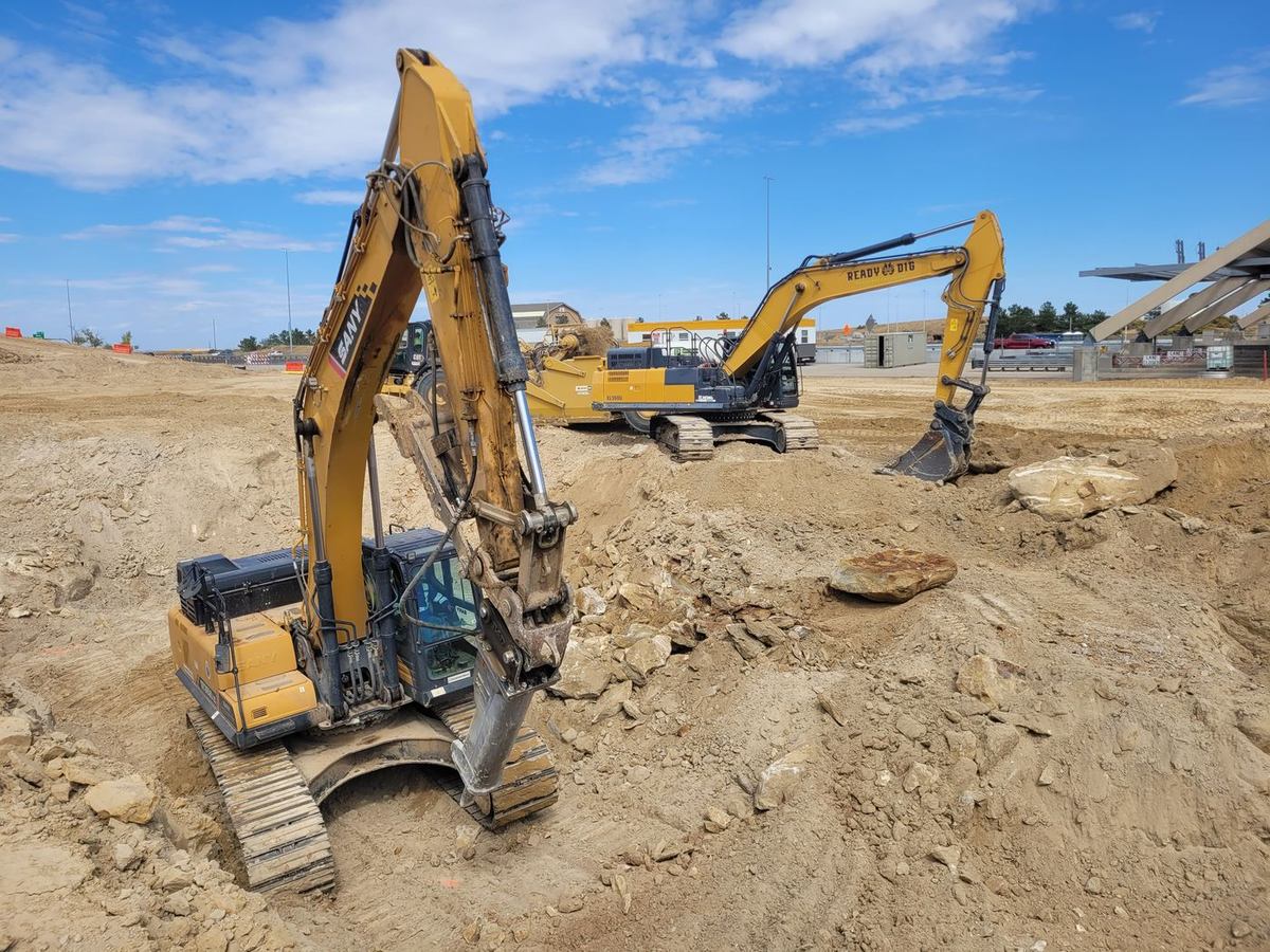 Excavator with a hydraulic hoe-ram breaking rock in a trench