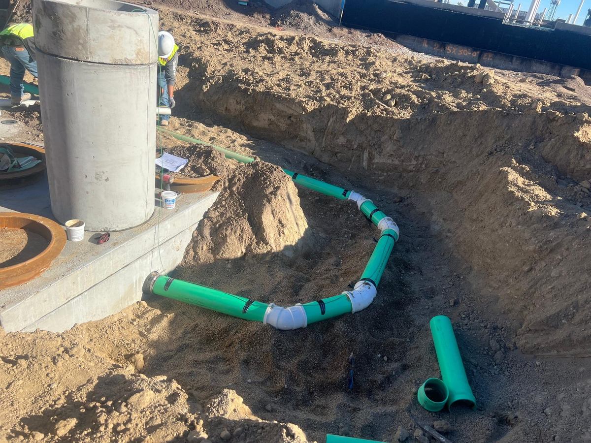Sewer line routed around a cast-in-place manhole base