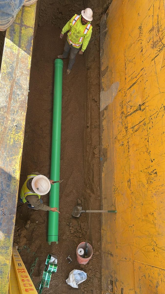 Workers setting sanitary sewer pipe in a shored trench