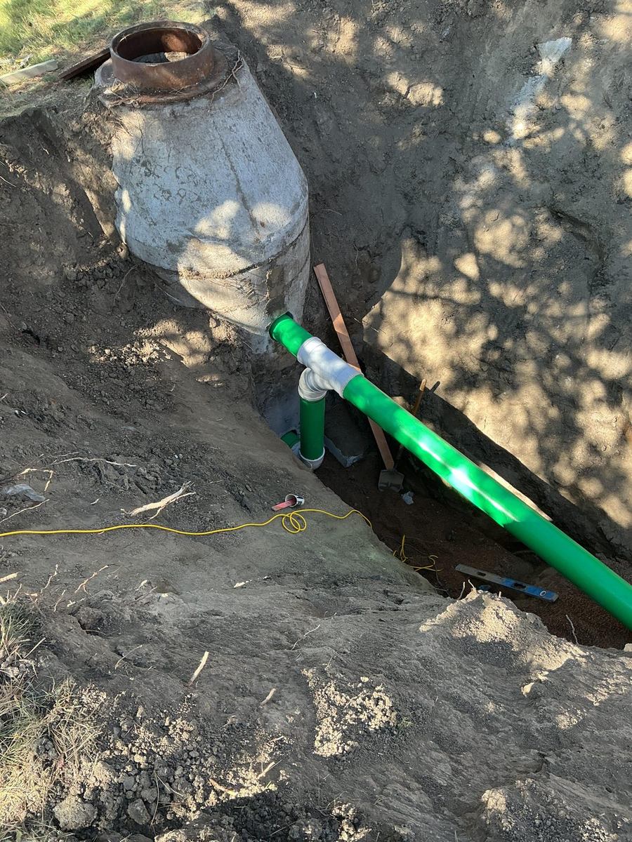 Green sewer pipe with a wye fitting tied into a concrete manhole