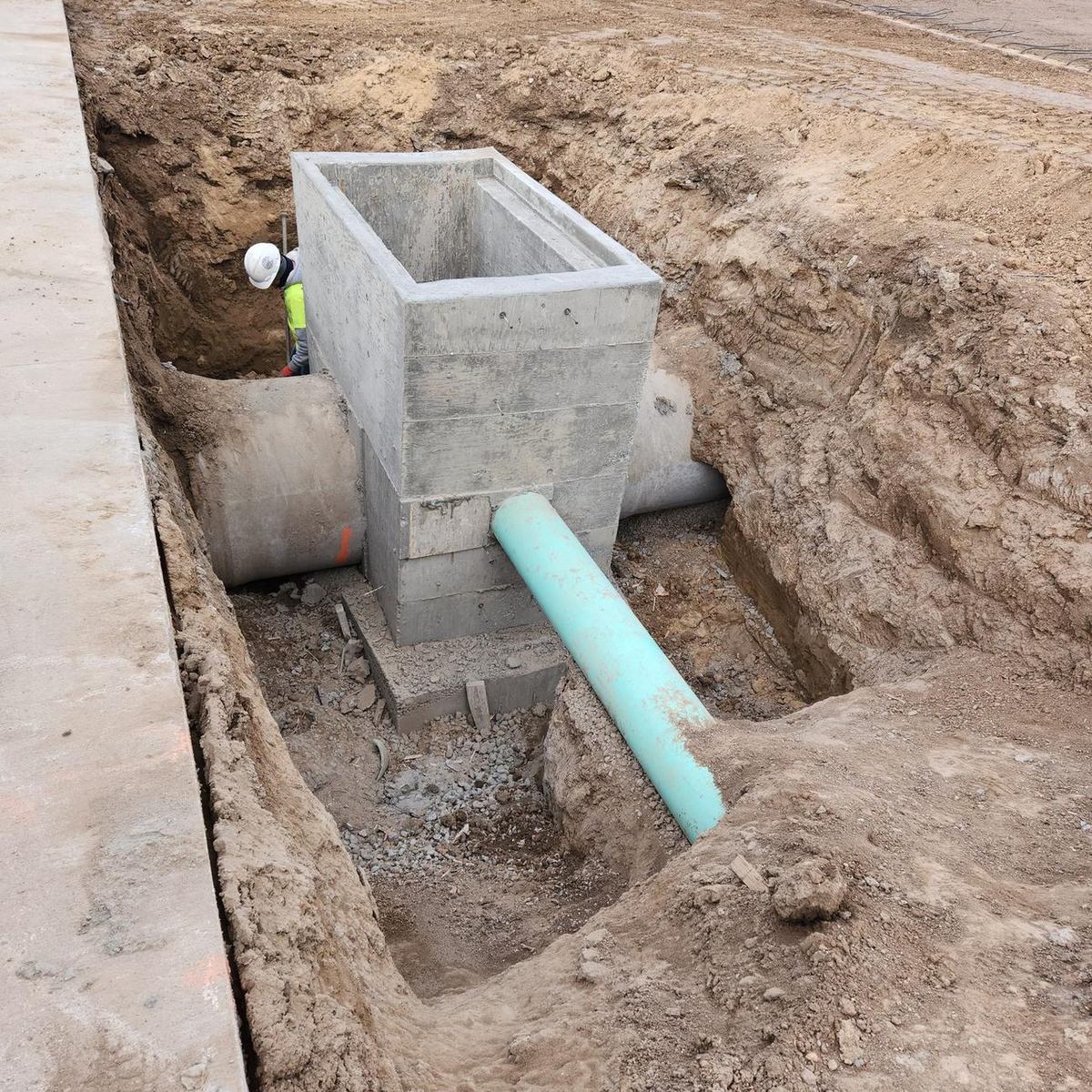 Completed cast-in-place concrete storm box structure with pipe connections