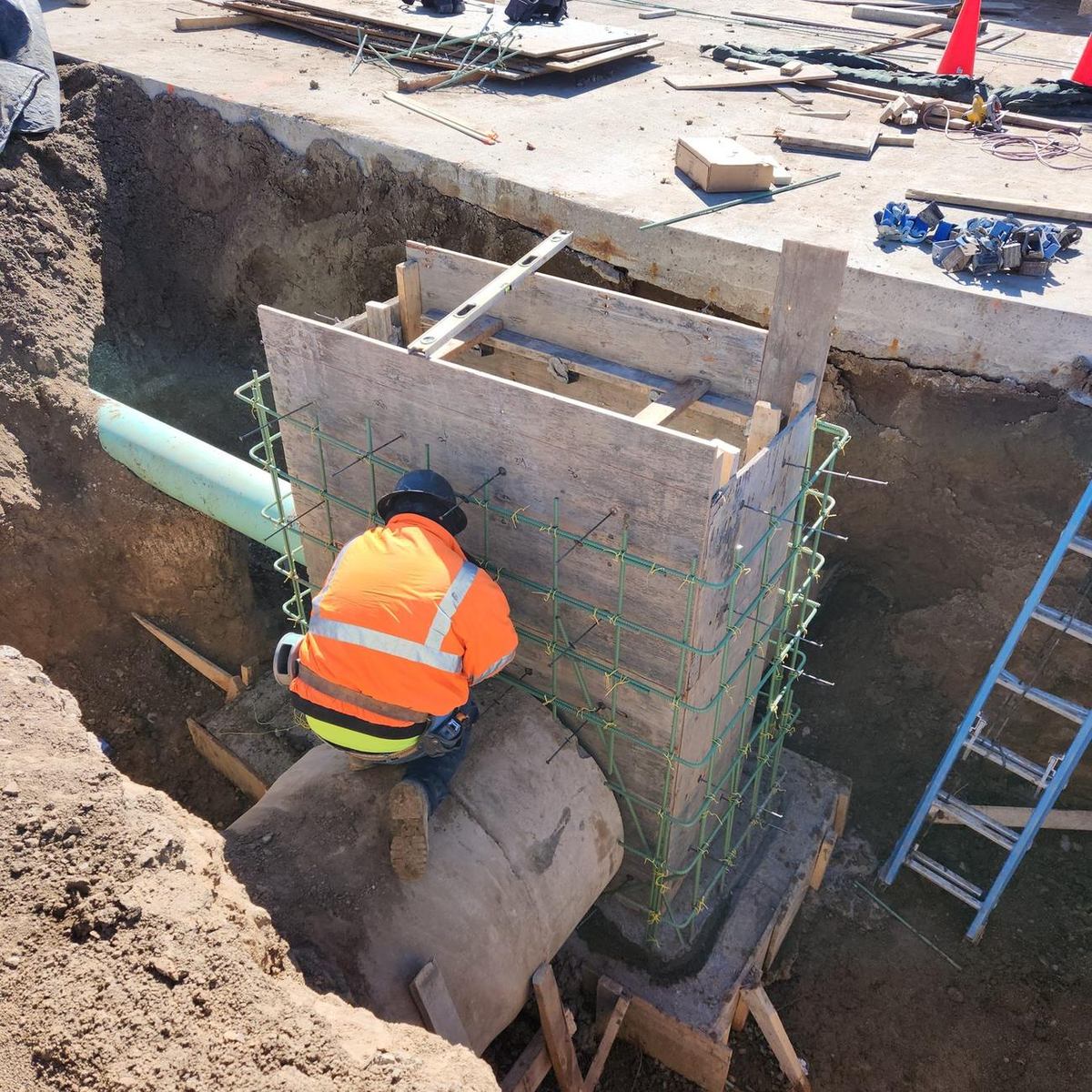 Worker tying rebar and setting formwork for a cast-in-place storm structure