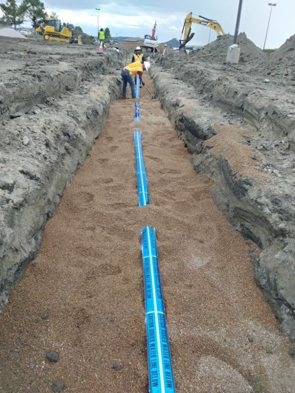 Pipe bedding with buried-water-line warning tape in the trench