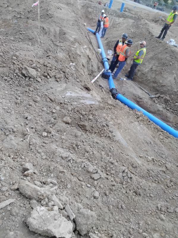 Crew making a C-900 pipe joint connection in the trench