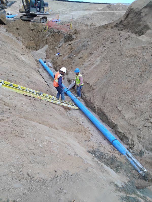 Two workers assembling C-900 water pipe in a trench