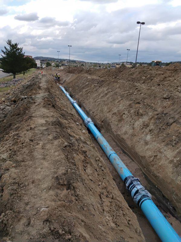 Long run of C-900 water main in an open trench along a roadway